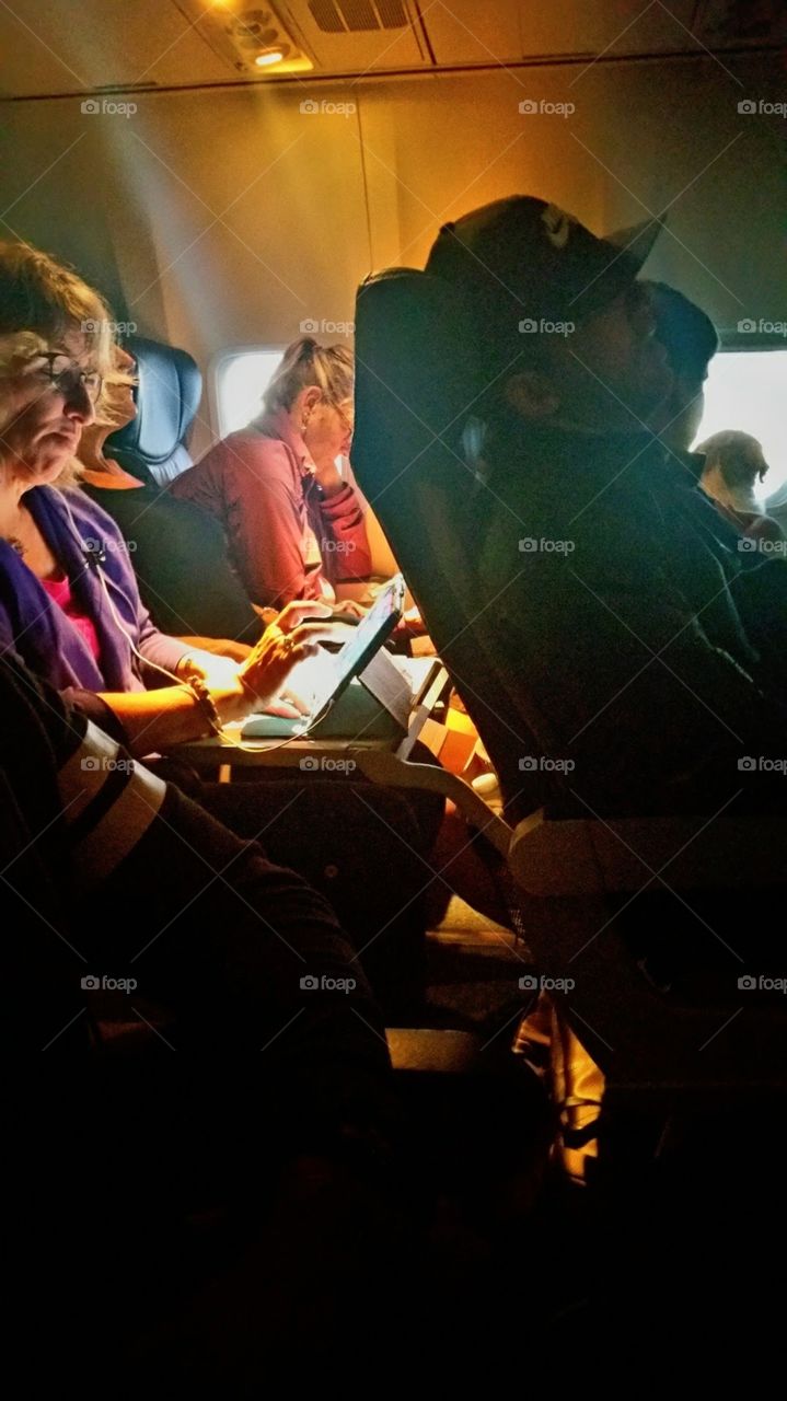 Women working on sports page on early morning flight to Fort Lauderdale