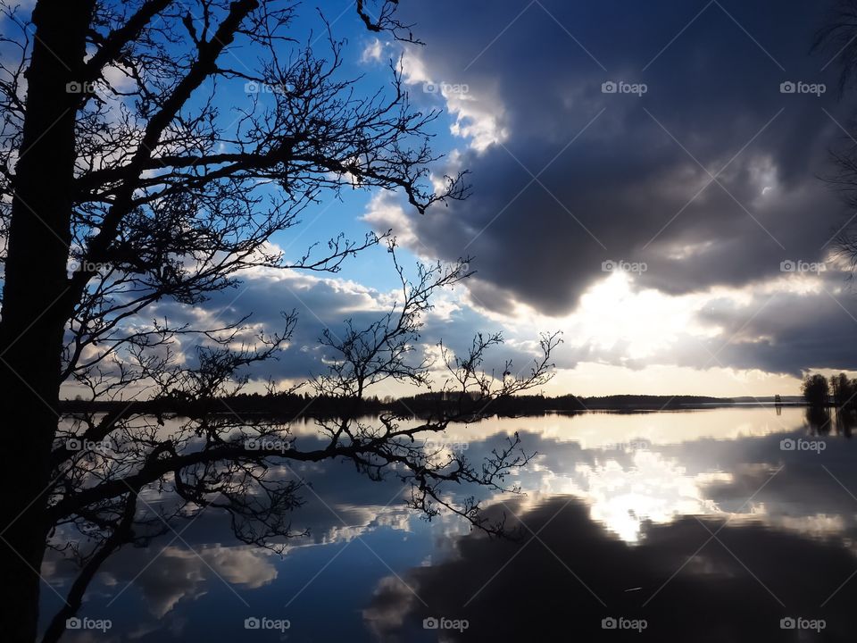 Cloudy sky is reflected on the surface of the water. Beautiful spring weather. 