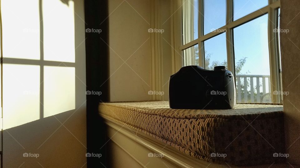 A wider view of a camera on a window seat with morning sun shining in.
