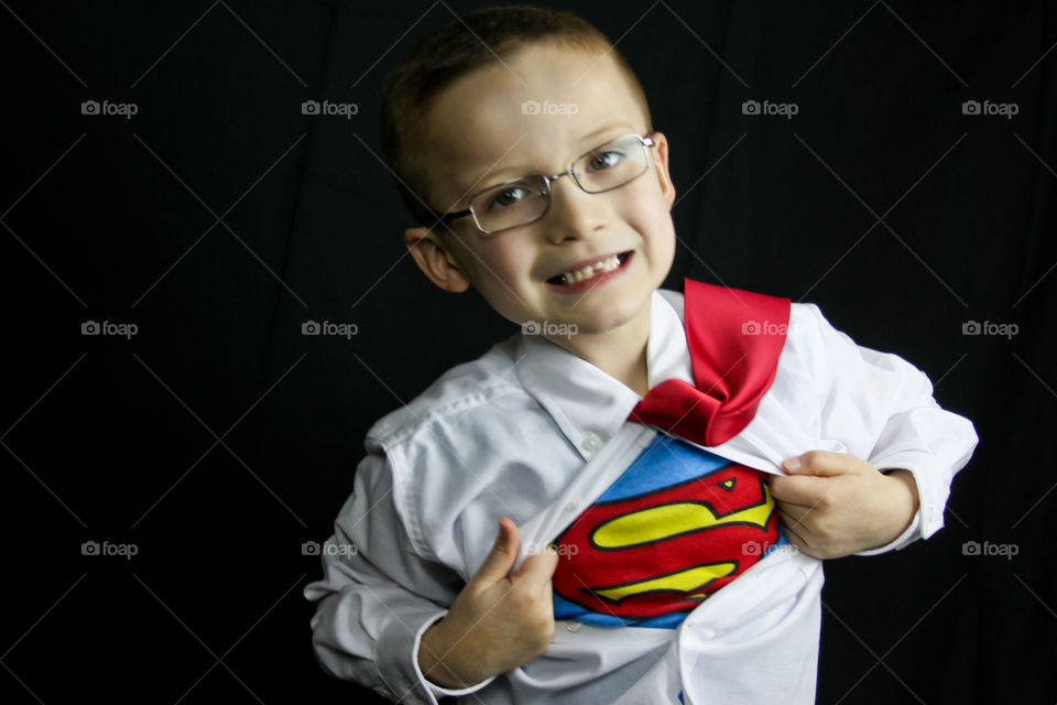 A boy dressed in a Superman costume pulls off his outer shirt