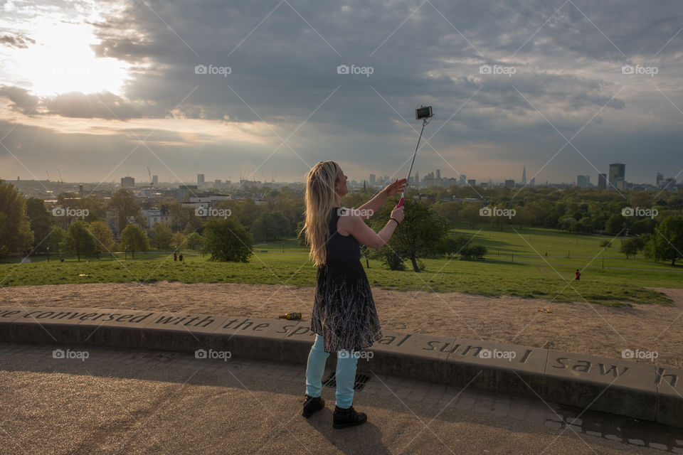Woman taking a Selfie in Primrose Hill park in the morning in London.