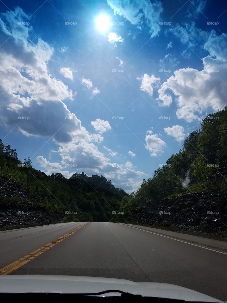Brighty Cloudy Blue Sky Above Low Hills and Open Road