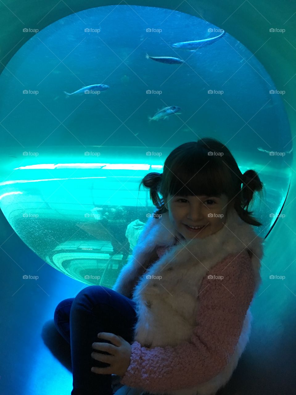 Happy girl sitting in front of aquarium