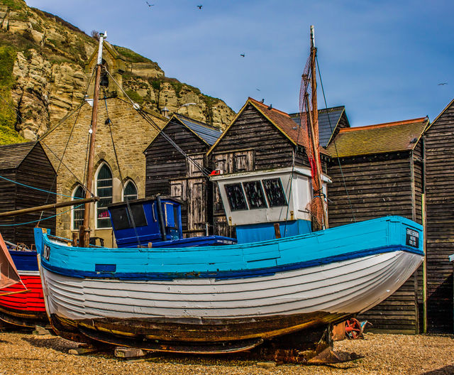 A fishing boat sits amidst the fisherman’s hut, under the cliff at Hastings, UK 