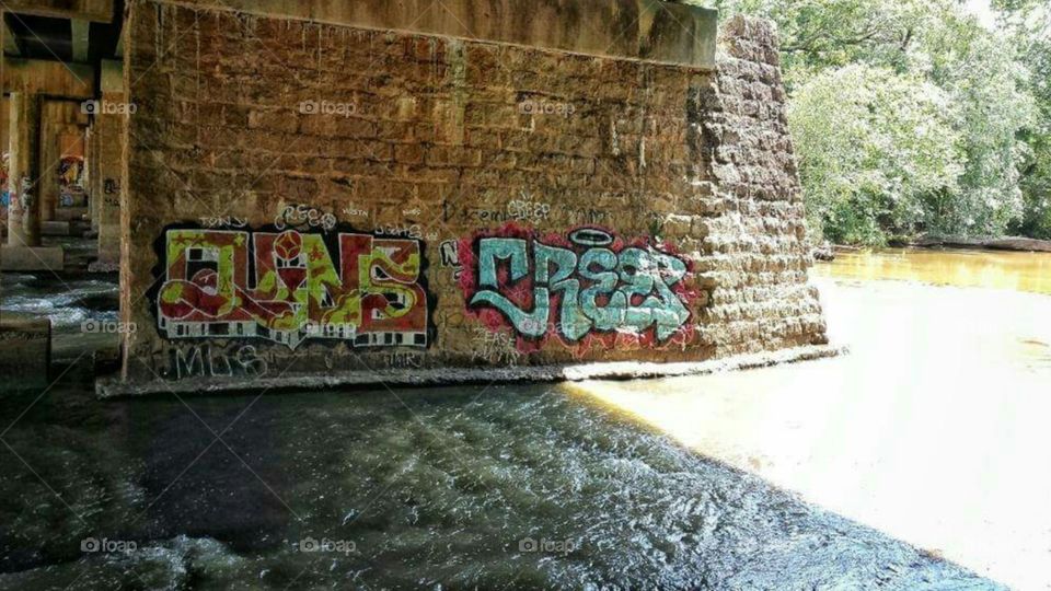 River under bridge with graffitti