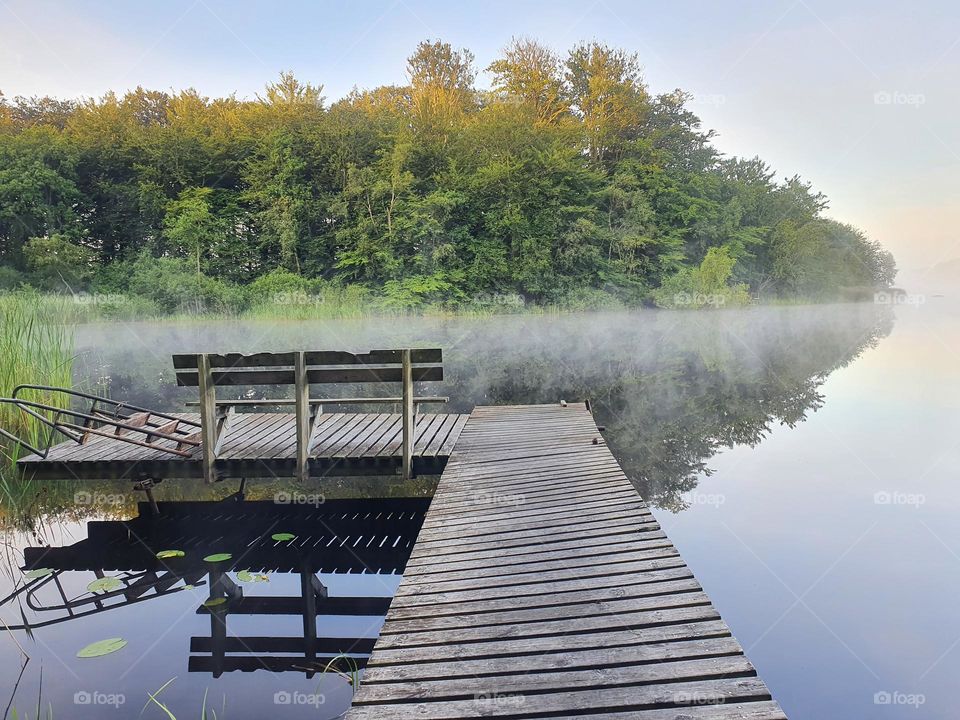 jetty at a lake. It is sunrise and the fog is lifting.