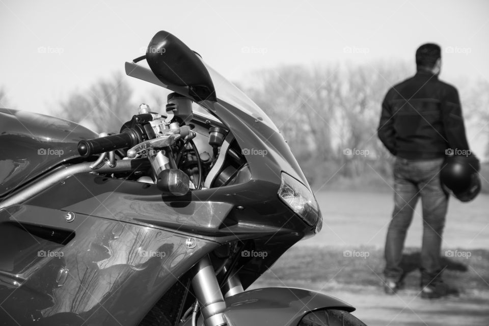 Sport motorcycle parked besides river. Black and white photo.