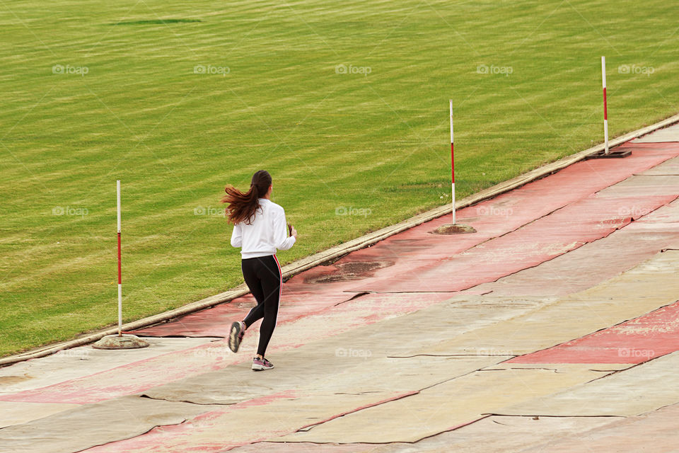 Back side view of running girl in the stadium