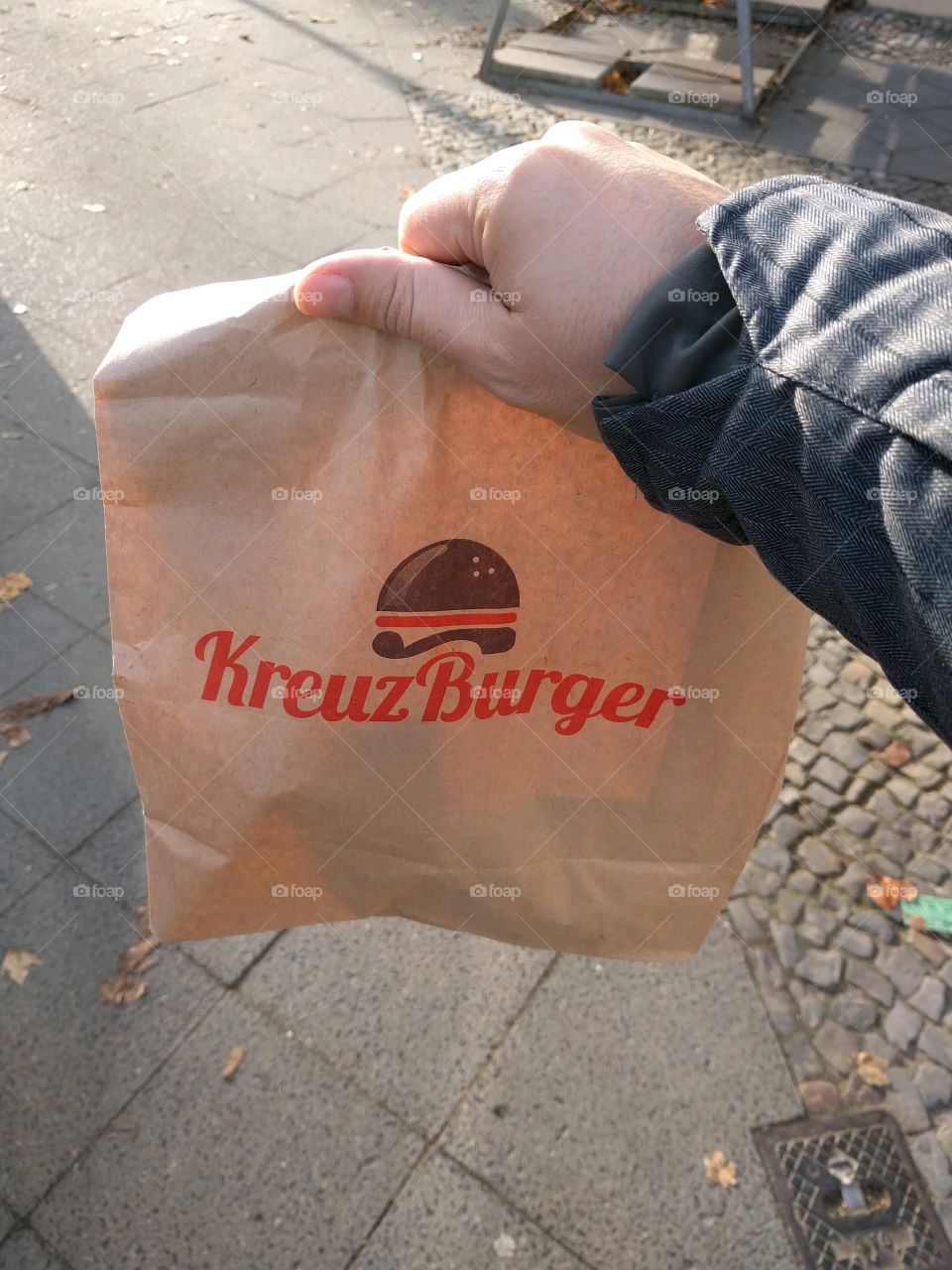 Hand holding take away hamburger bag