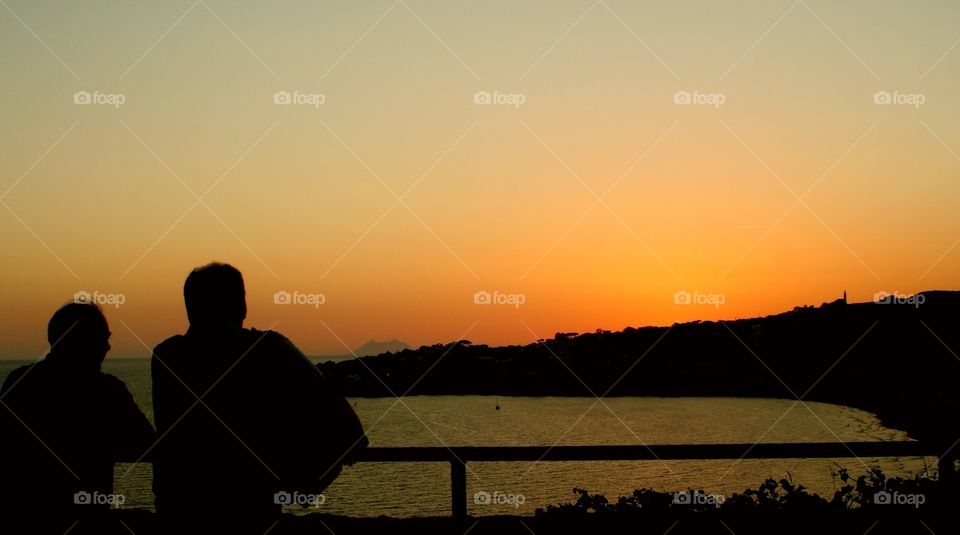 Two old men looking at sunset during a vacation day with their group.