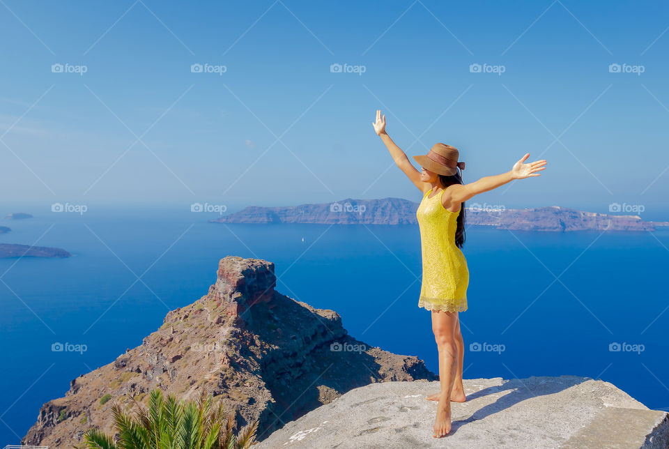 Woman standing with arms raised on top of rock