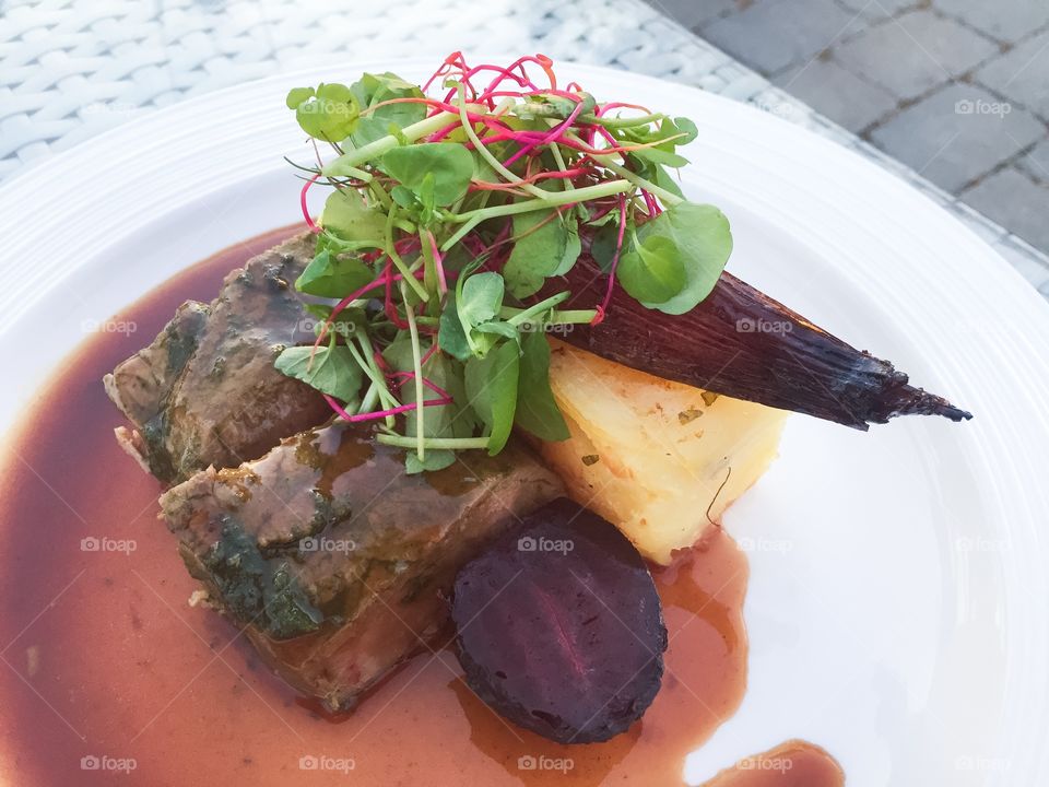 Exclusive main course of fillet of beef and potato cake and gravy, eaten on the terrace at sunset.