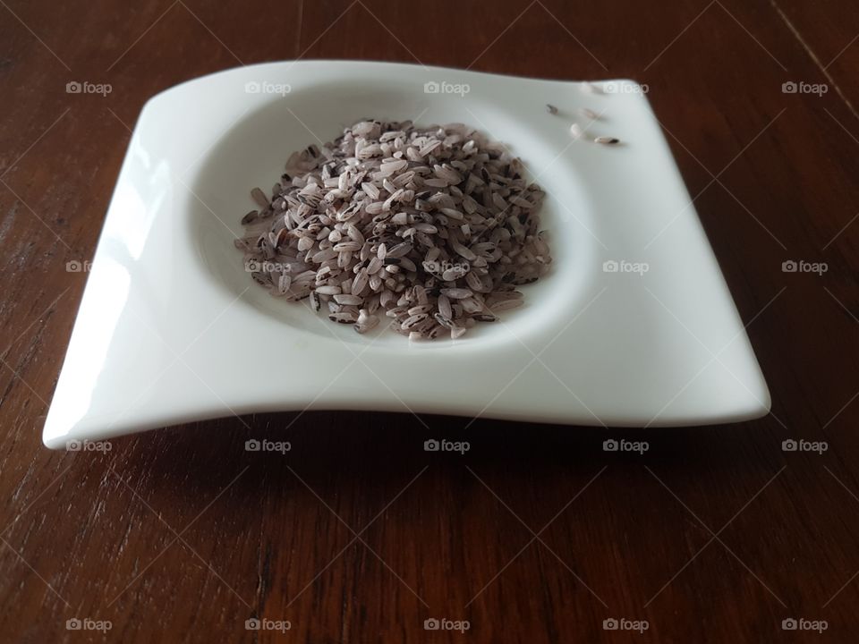 Isolated image of healthy organic red Bario wild rice grains from Sarawak, Malaysia on white plate