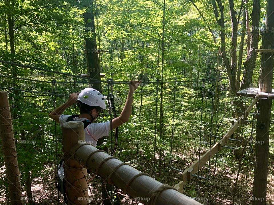 Boy climbing on obstacle course in forest