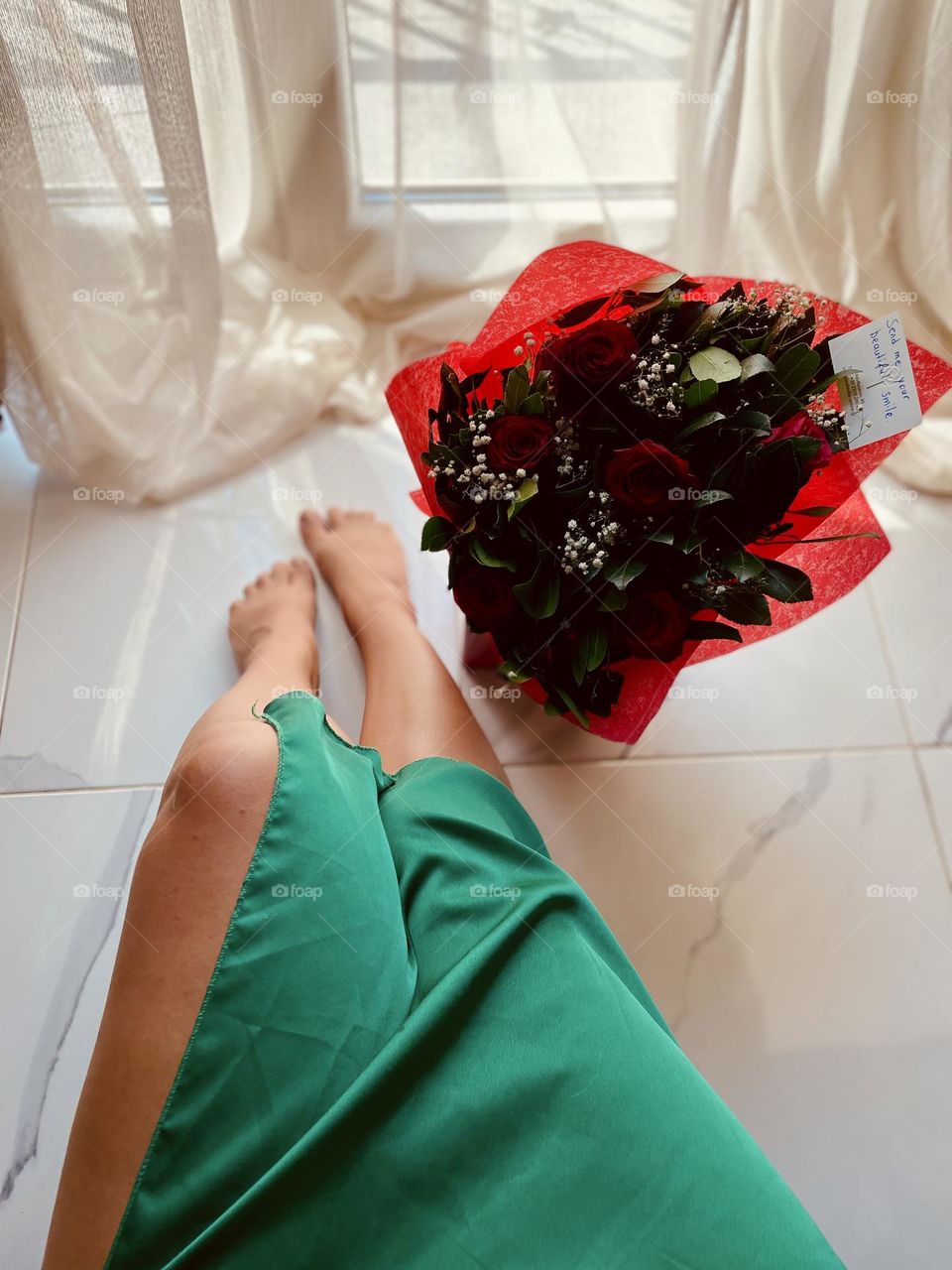 Naked legs in green dress with a bouquet 
