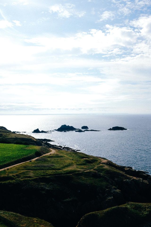 View Of Green Hills By Dark Blue Water