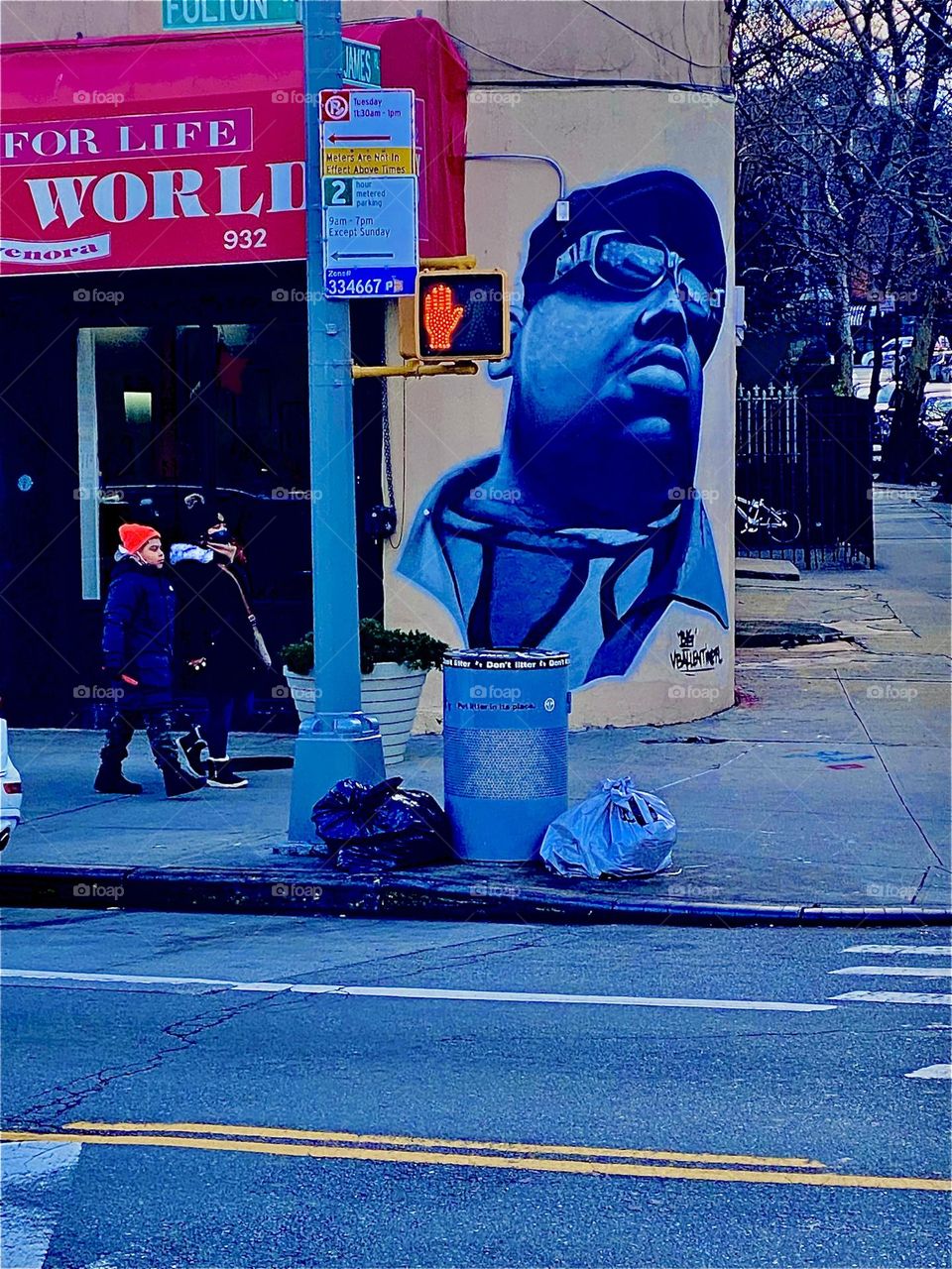 Across Fulton St in Fort Greene, Bklyn, NY the graffiti art portrait of the „Notorious BIG Christopher Wallace“ can be seen next to a traffic light signaling „DON‘T GO“ by showing a LED lit up hand making the „STOP“ sign. 2021. Hypnotic Productions