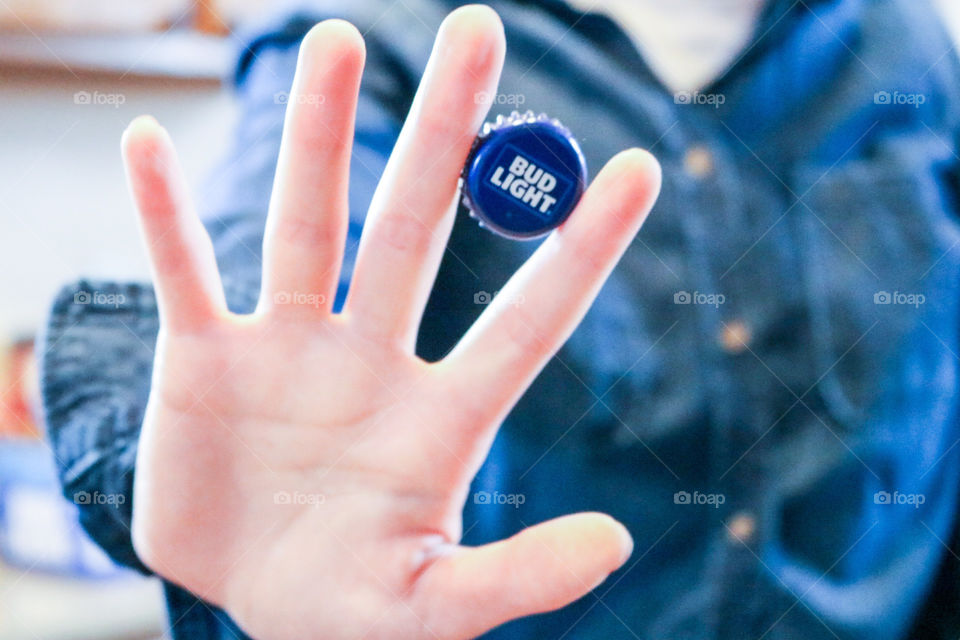 Hands up for Bud Light- person holding bud light cap between fingers.