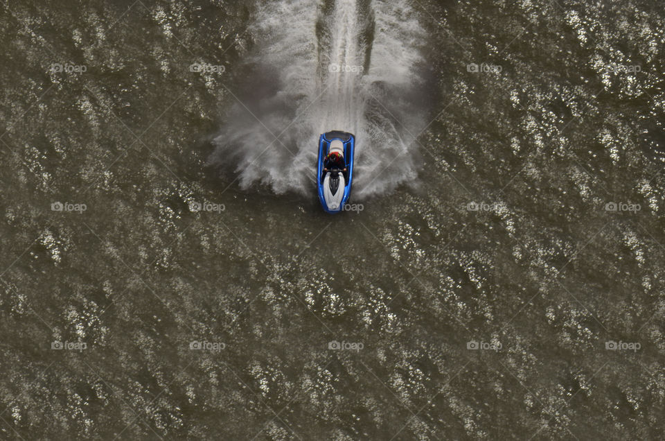 From an altitude measuring more than 400 feet atop the George Washington bridge a man rides a wave runner through the hudson.