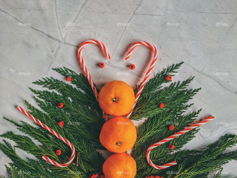 Christmas and New Year background with spruce branch, candies, decorations and tangerines Flat lay. Top view.