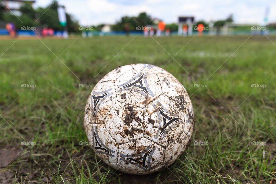Muddy soccer ball on a football field in Municipal Stadium Nakhon Ratchasima.
