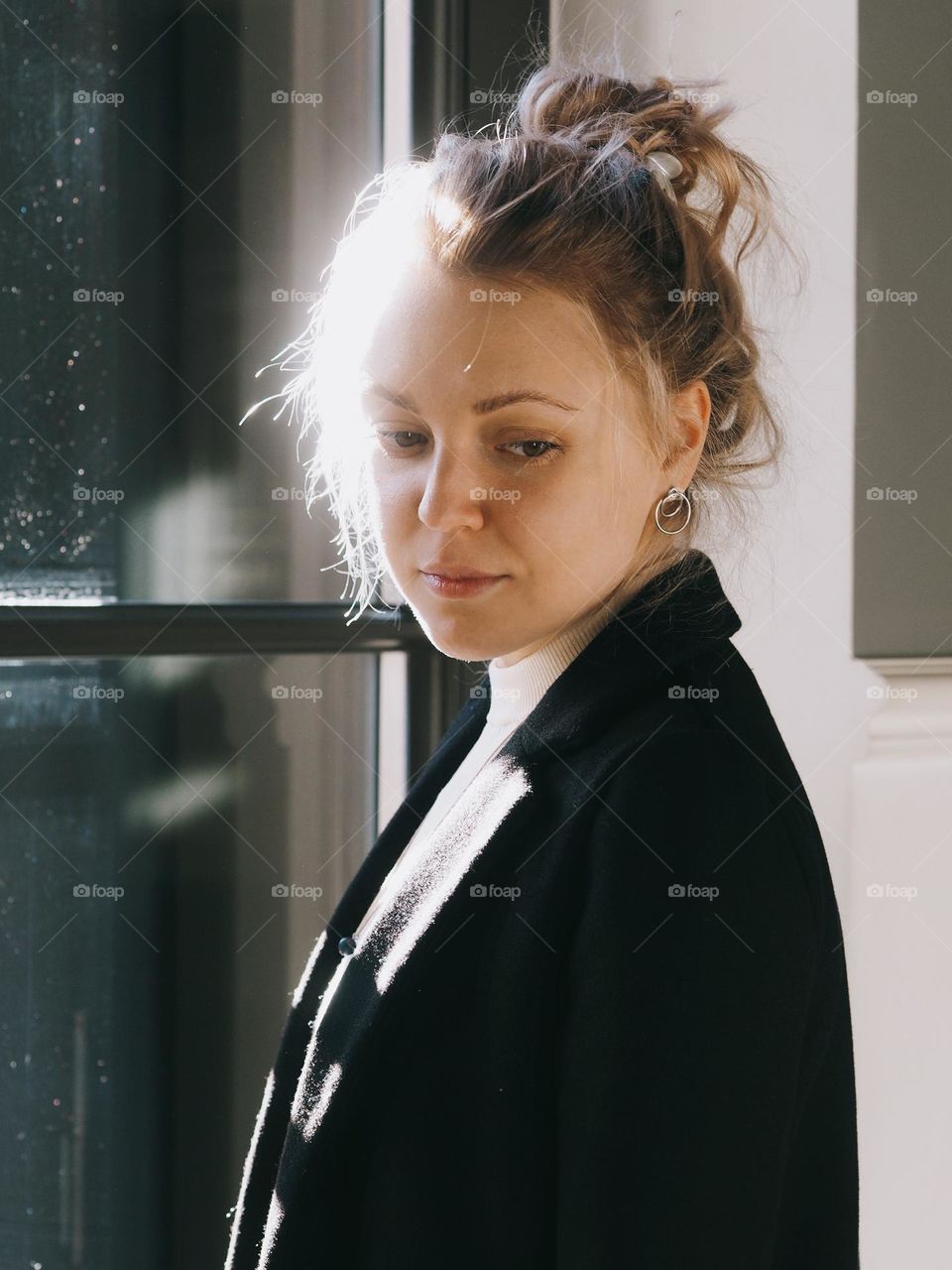 Portrait of a young blonde girl at a window on a sunny day, portrait of woman 