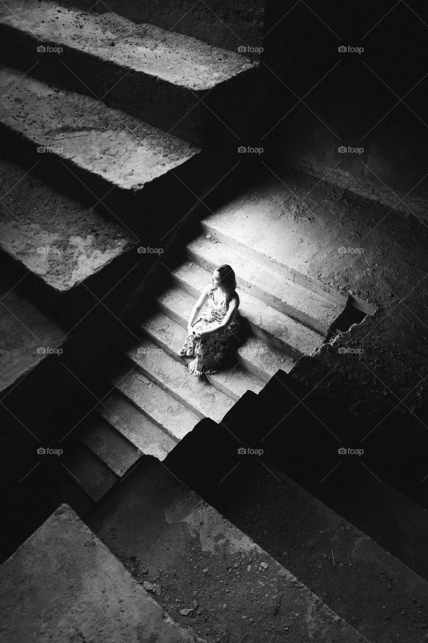 a lady sit down in the middle of the stairs. my eyes focus on the frame so I made an unique frame to make it good. using only available light from the location.