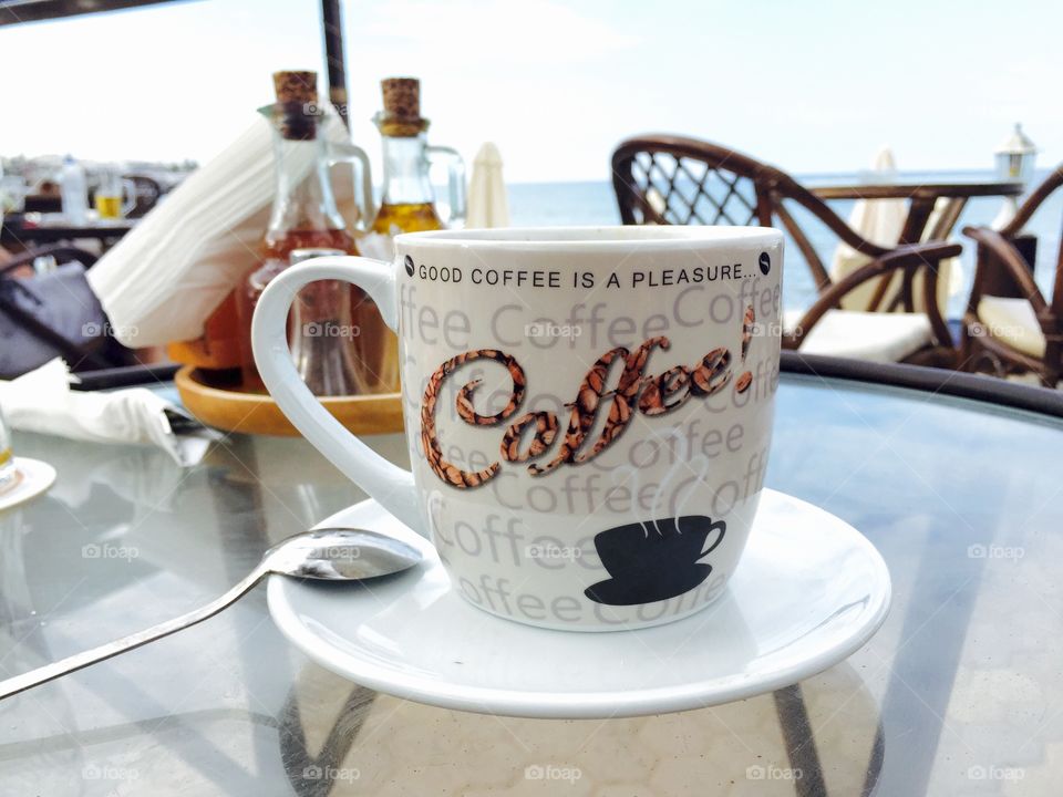 Coffee mug with the logo good coffee is a pleasure on a beach bar table