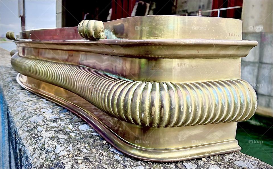 Angled to show the rounded edges of this elegant design piece fit for a castle, a modern times mansion or estate this large bronze fireplace fender was photographed beneath the Pulaski Bridge in LIC, Queens. 2022. Hypnotic Productions
