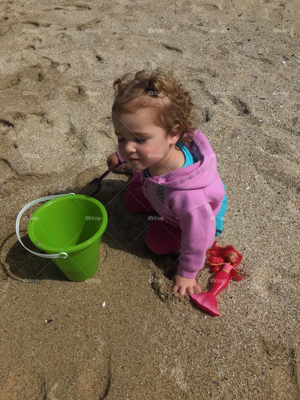 Baby in the sand with a bucket.