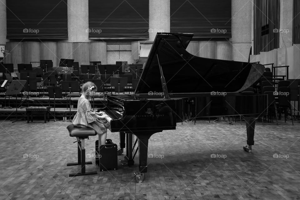 Little girl playing on grand piano.