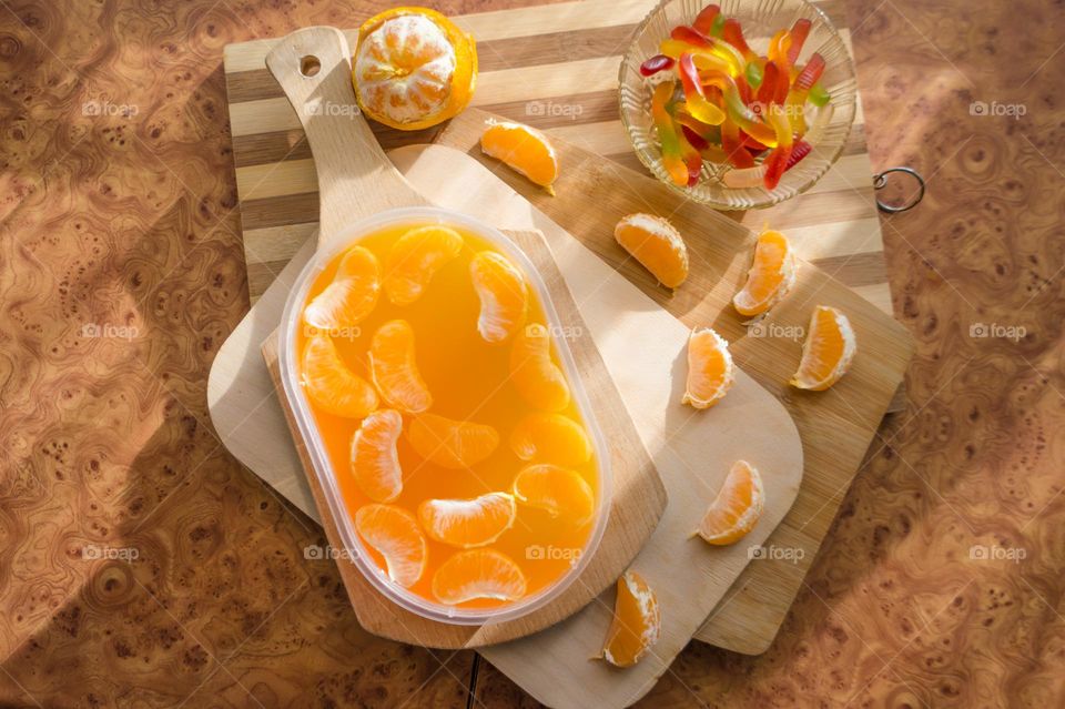 Delicious orange jelly with tangerine slices in a container and jelly worms.