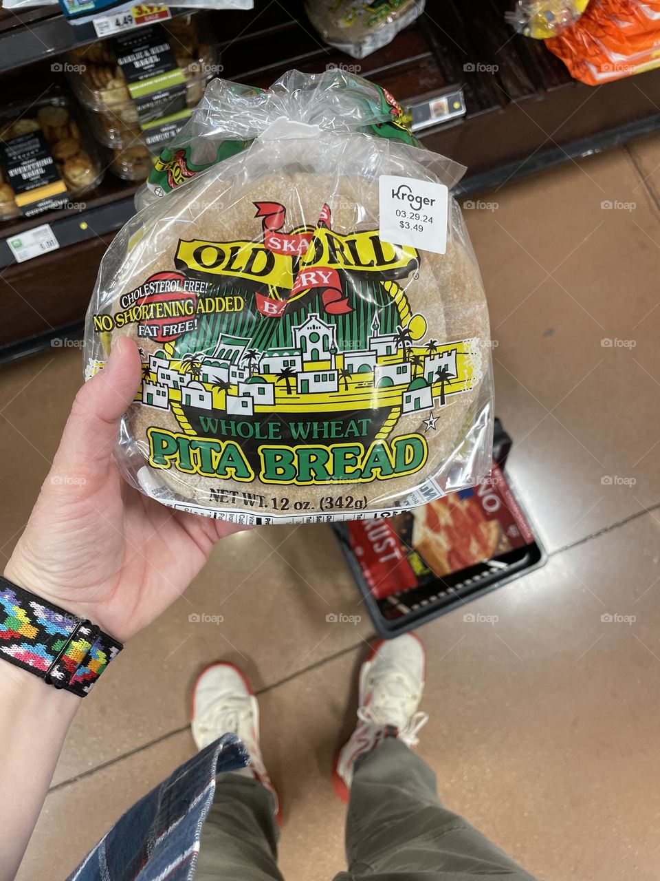 Shopping in a grocery store, buying pita bread at a grocery store, woman’s hand holding wheat pita breads