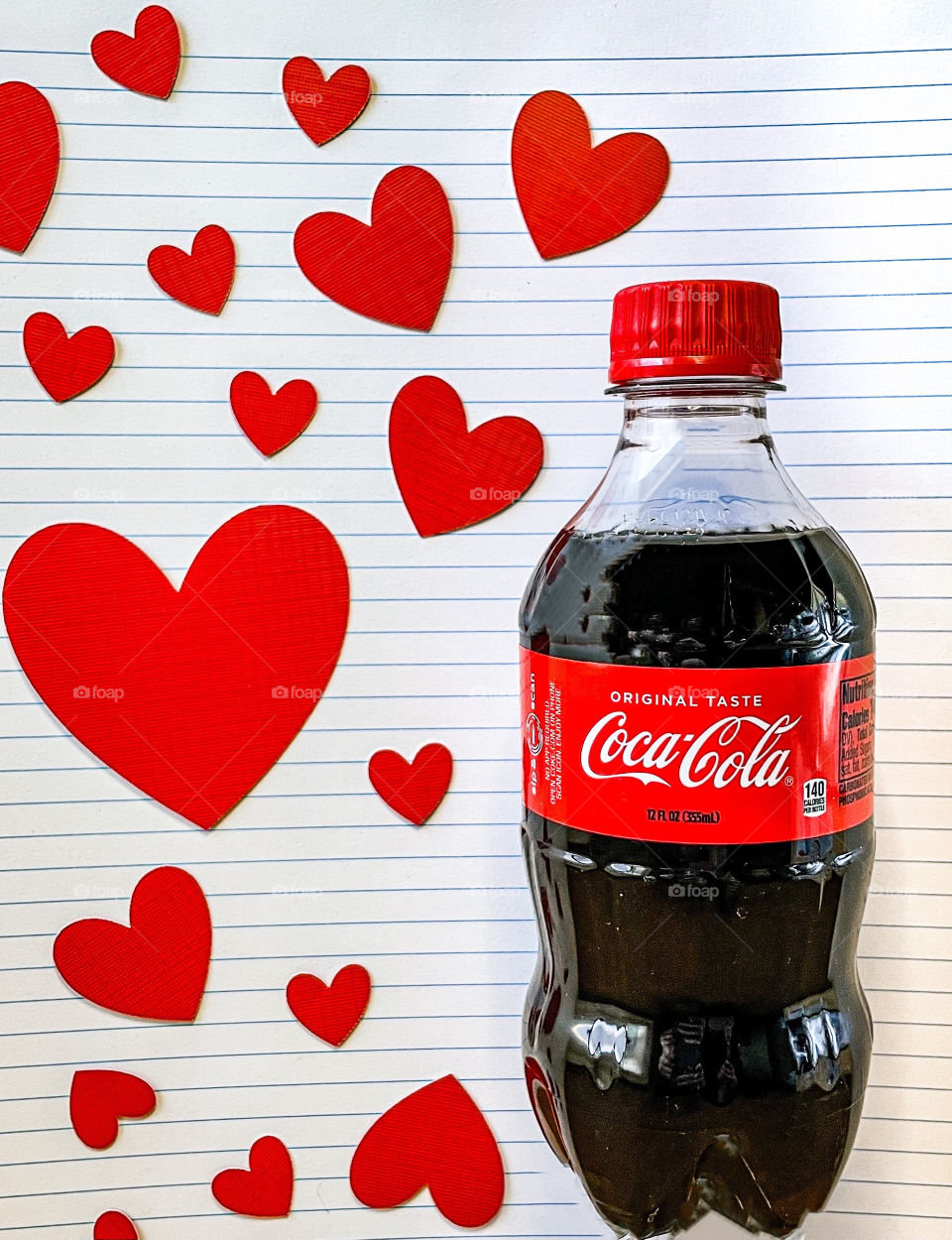 Coca Cola bottle with school writing paper background with red hearts. 
