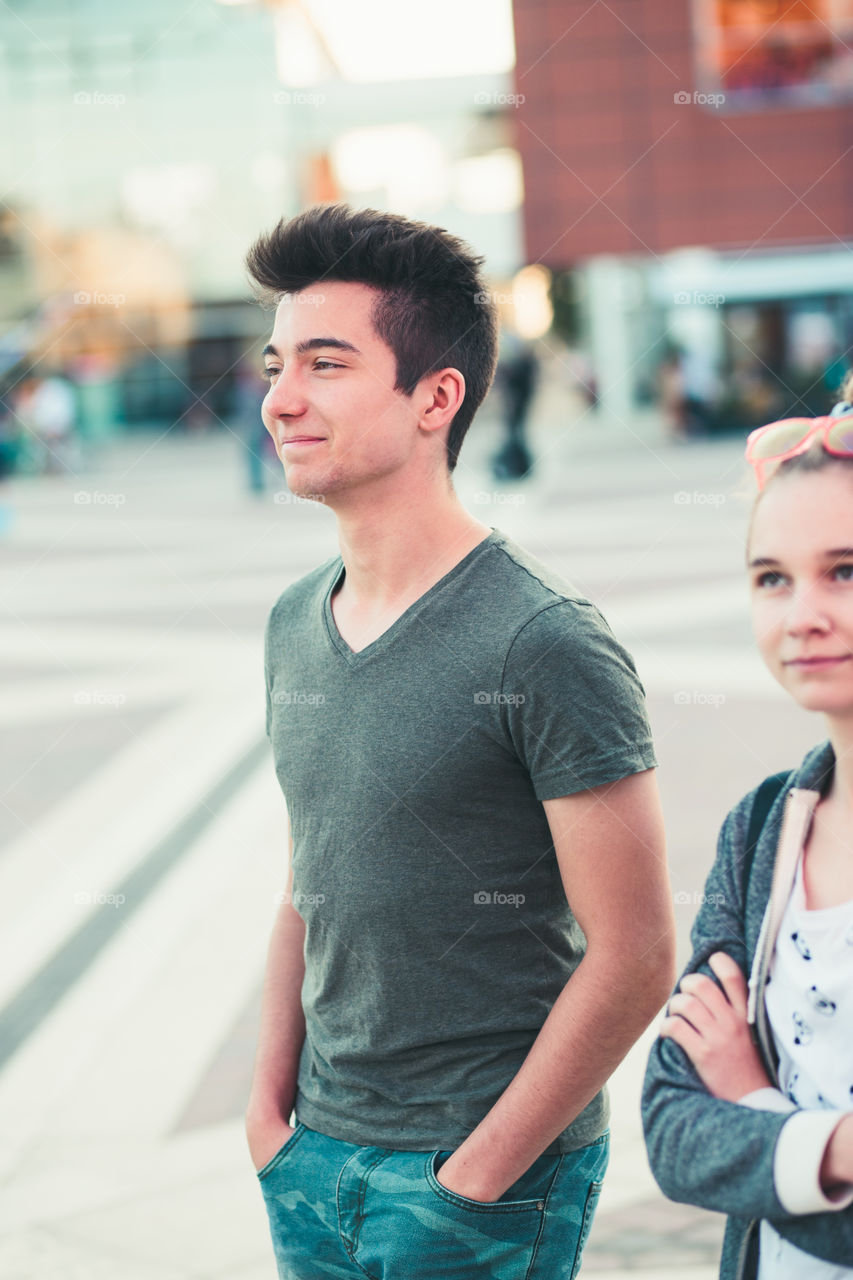 Couple of friends, teenage girl and boy,  having fun together, walking in center of town, spending time together