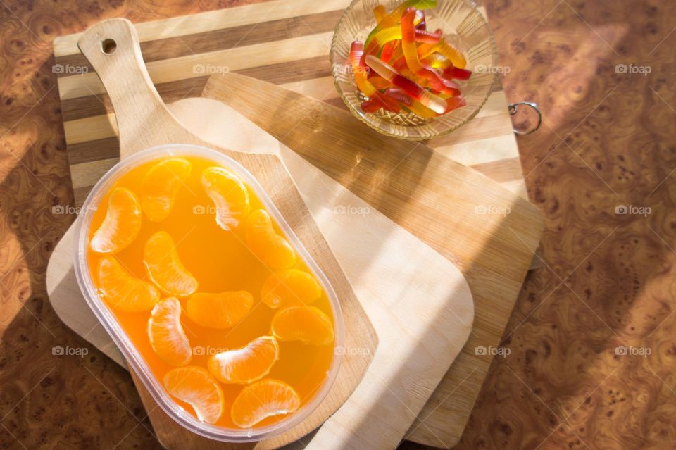 Delicious orange jelly with tangerine slices in a container and jelly worms.