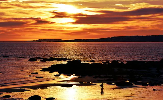 Silhouette of two people walking at beach