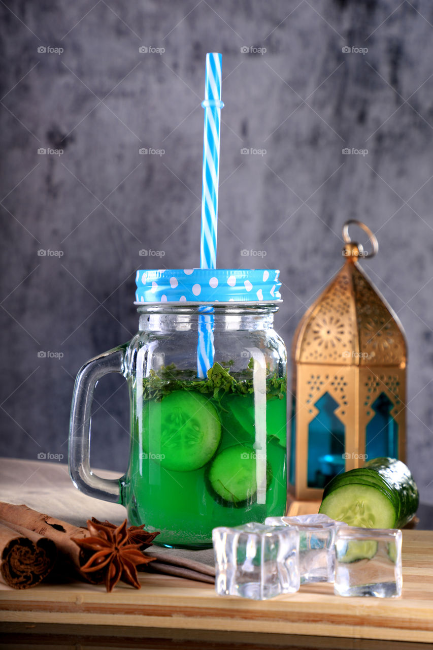 Mason jar with cucumber juice, ice cubes and lantern