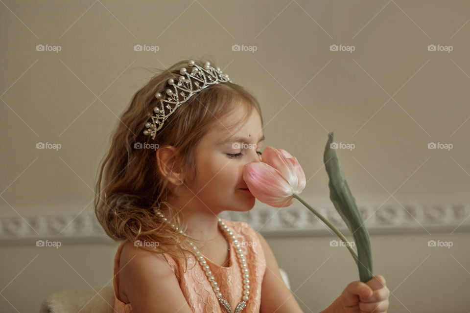 Vintage portrait of a beautiful little girl in pearl crown with tulip flower