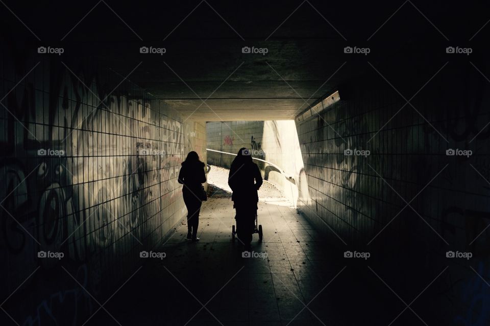 Zwei Frauen gehen mit einem Kinderwagen durch eine Tunnel.