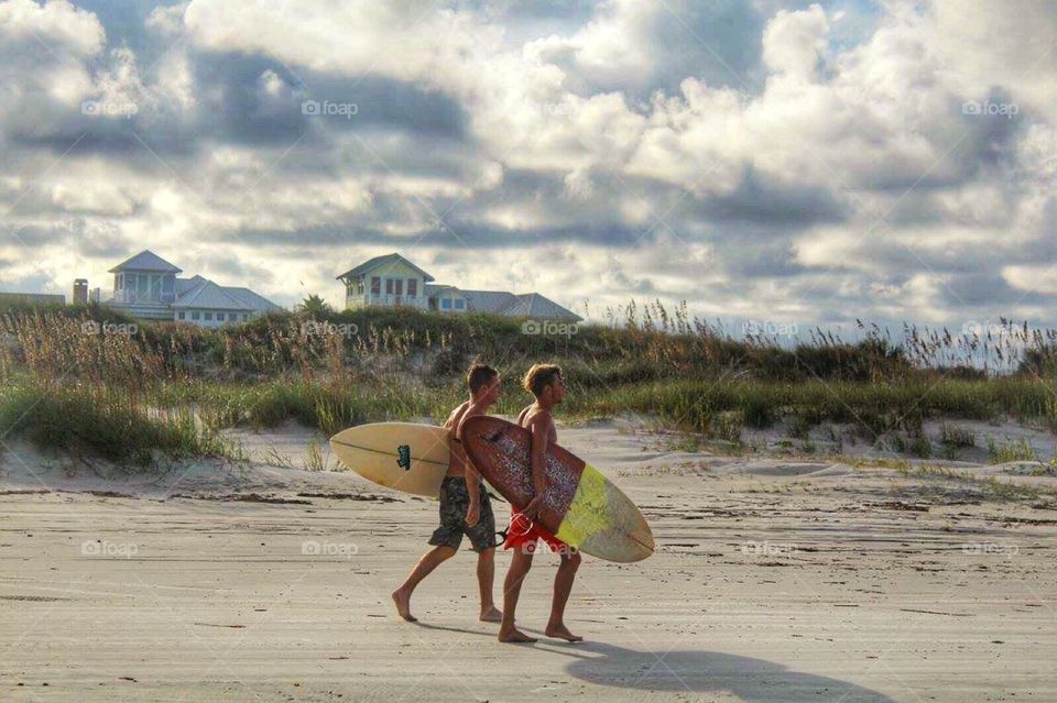 Guys walking on beach with surfboard 