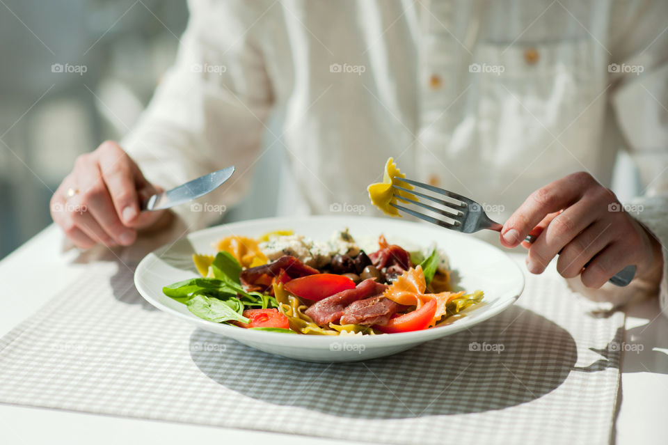 close-up of a young man eating a salad in a light kitchen