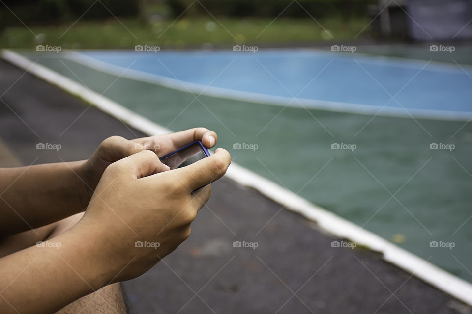 Hand holding telephone Background on basketball court.