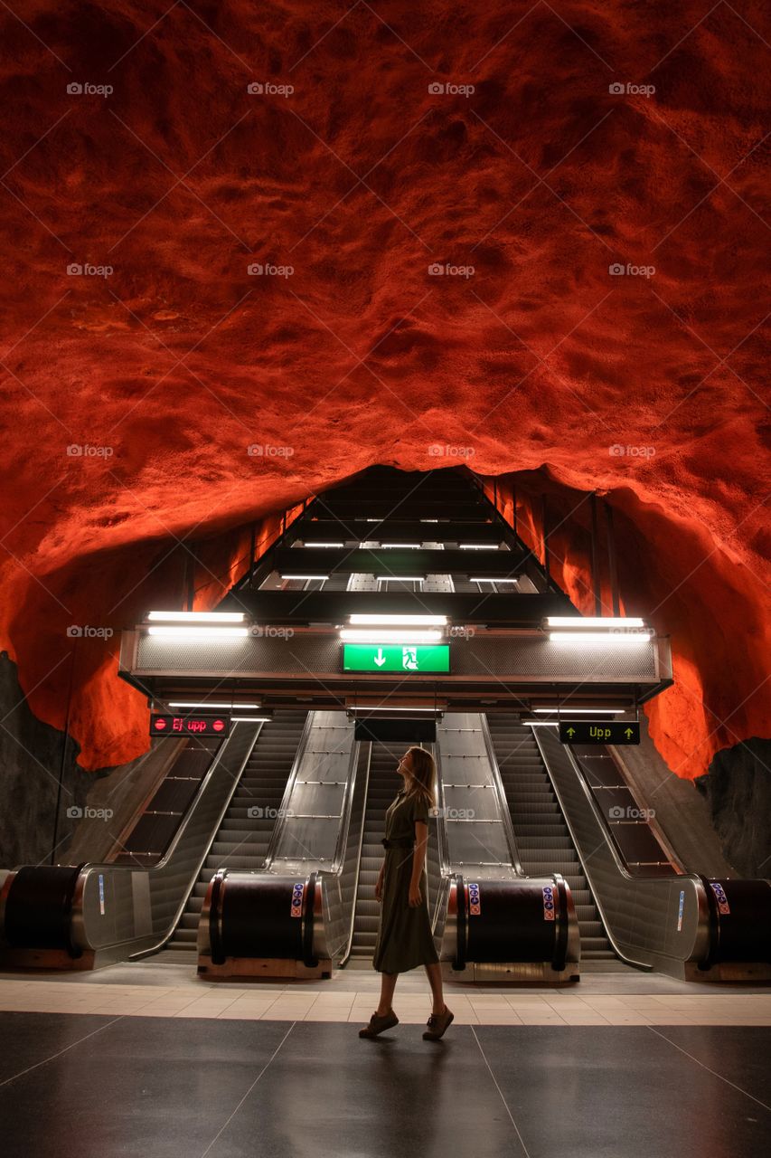 Girl in an underground escalator with a fire wall