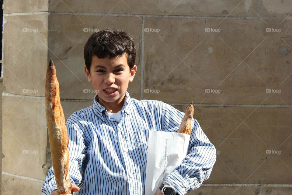 Young boy, son travelling in Paris. International travel adventure to bakery for baguettes.
