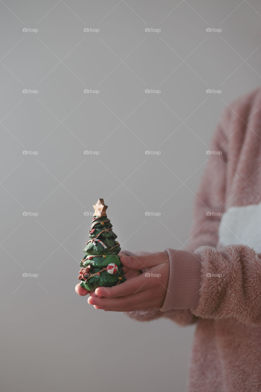 Close shot of young girl wearing warm sweater holding Christmas tree figurine