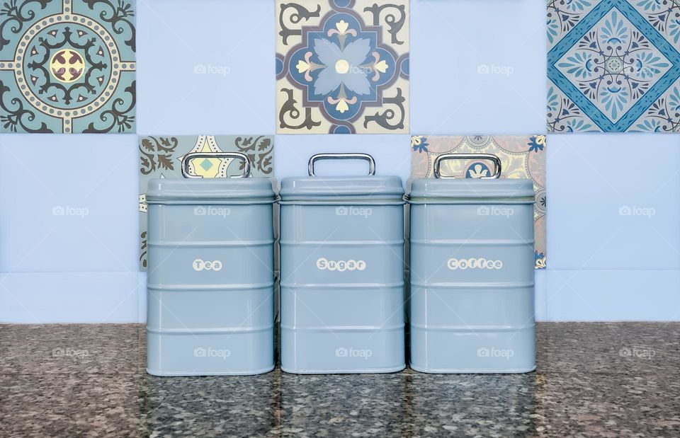 Baby blue kitchen containers on a granite worktop in front of pastel shade tiles