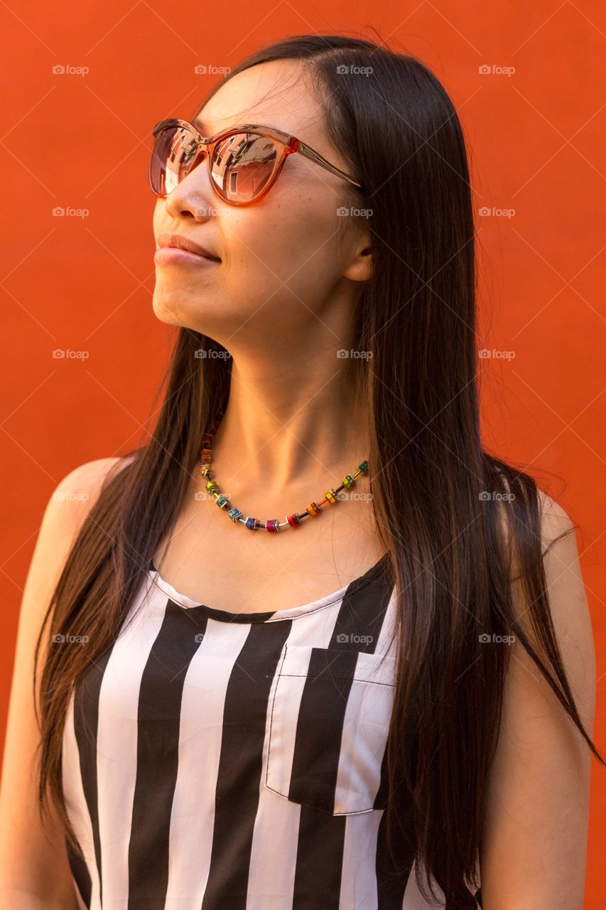 Beautiful young woman against orange background