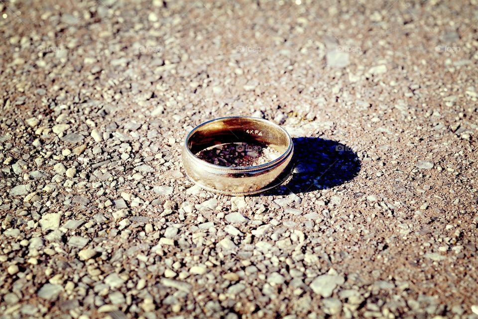A wedding band sits atop a stone ledge.