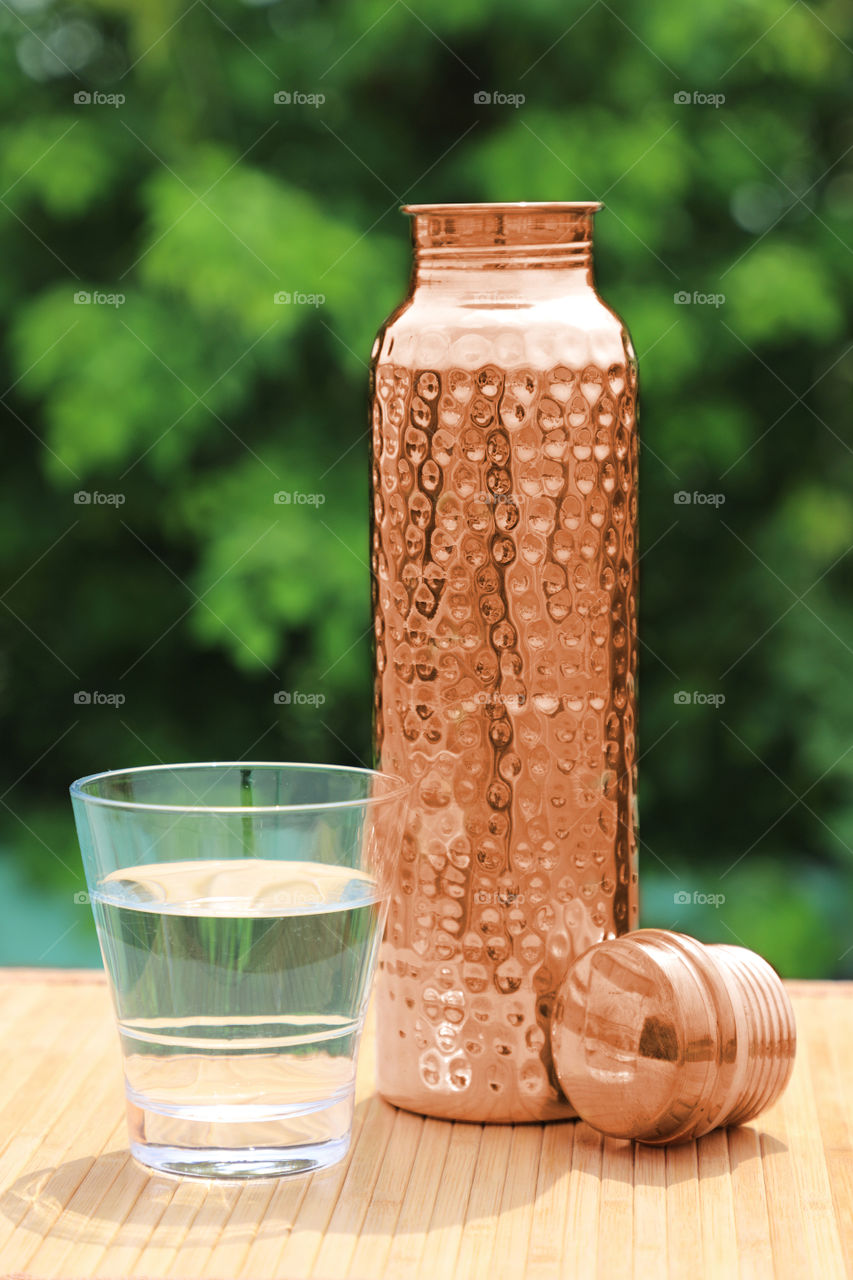 Indian handmade traditional copper water bottle with a glass